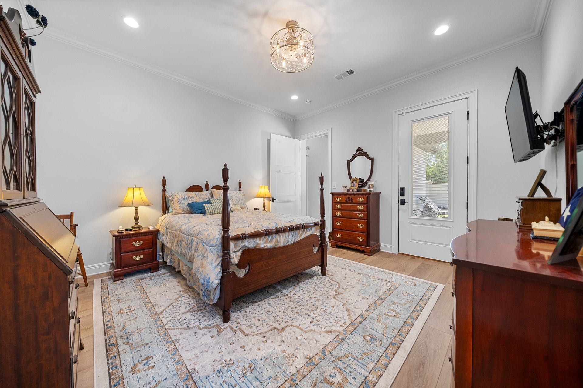 A bedroom with a large bed , dresser , nightstand and television.