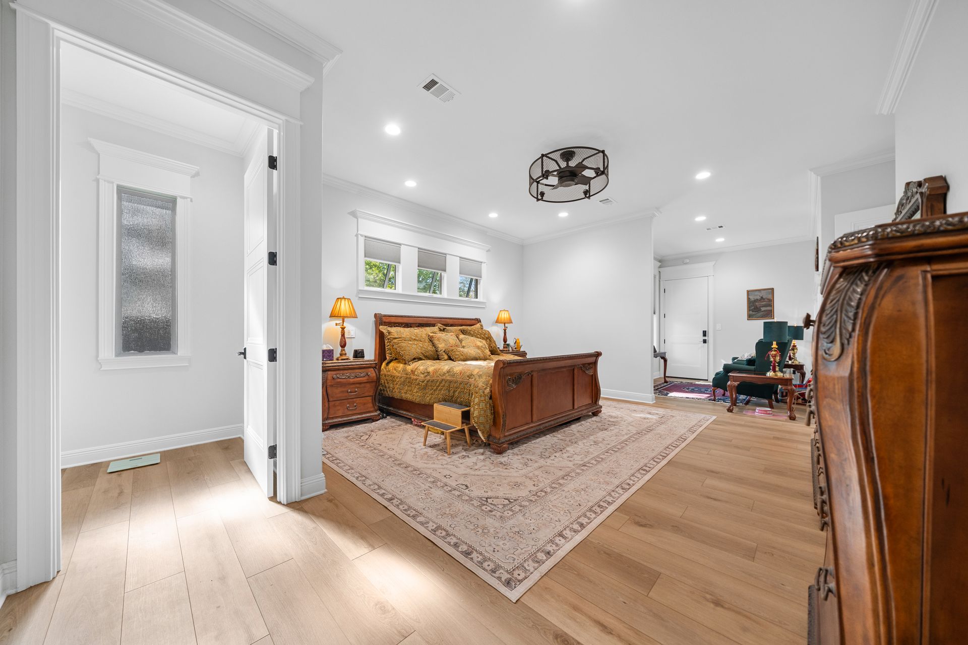 A large bedroom with a king size bed , rug , dresser and chair.