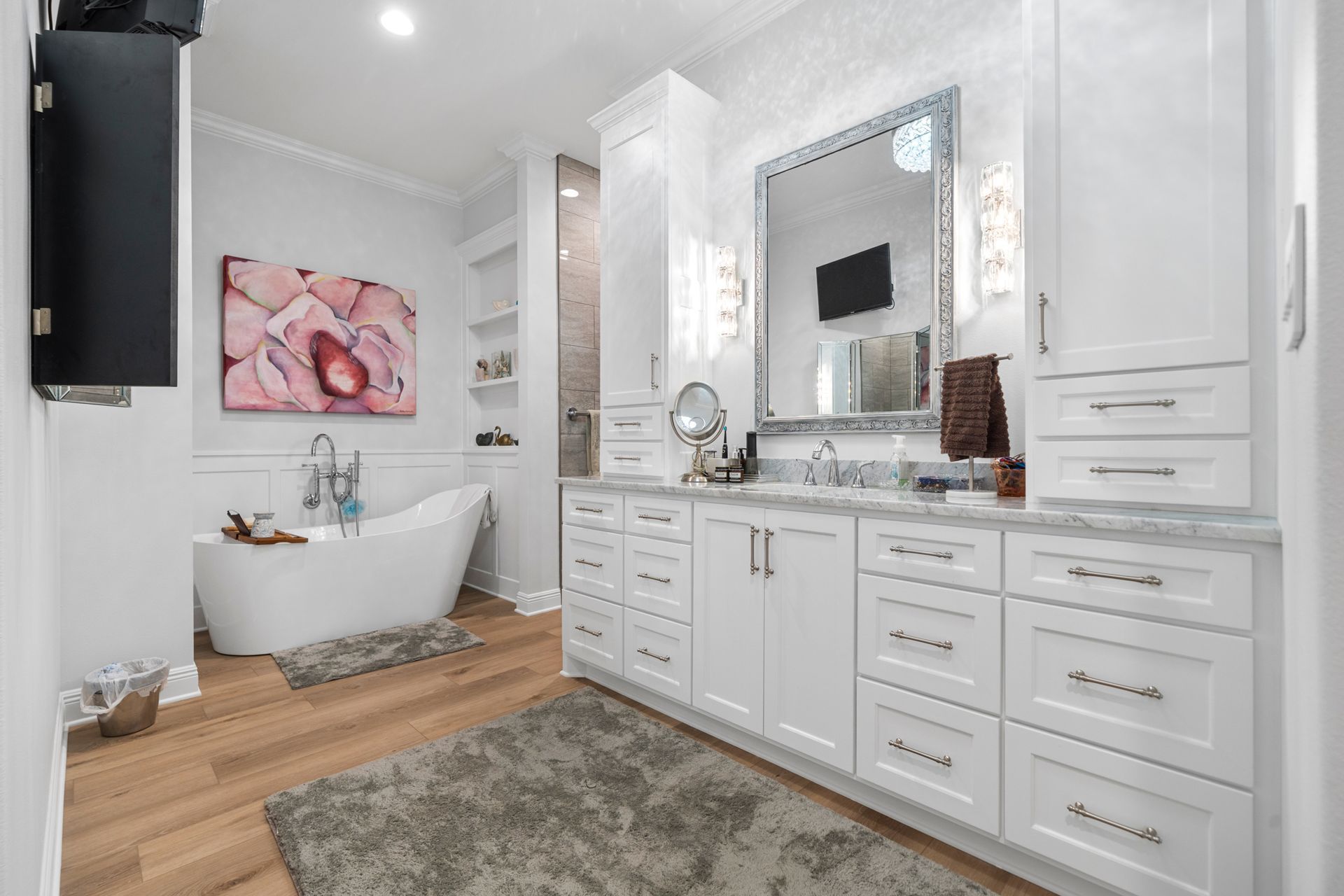 A bathroom with a tub , sink , mirror and cabinets.