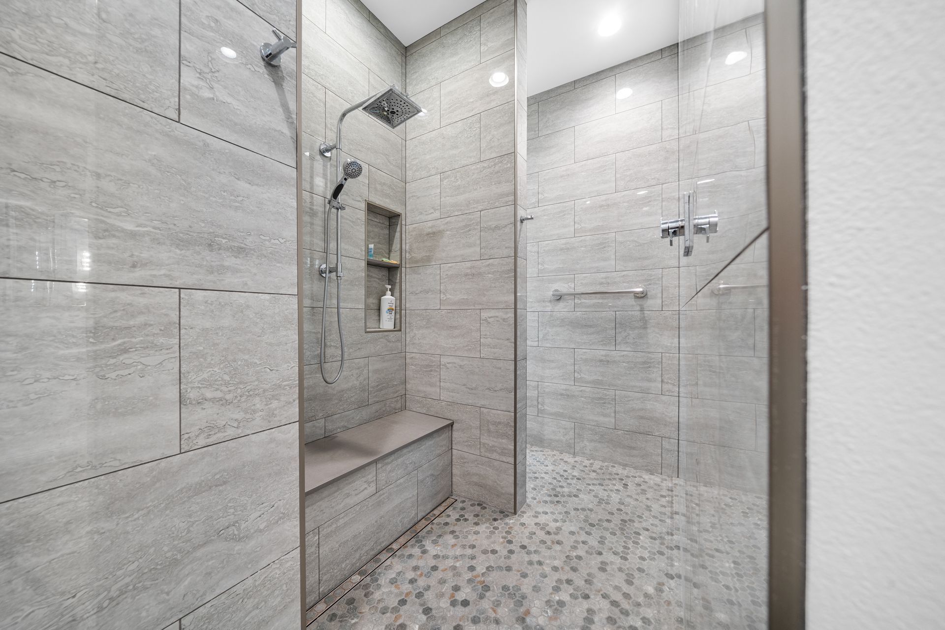 A walk in shower with a bench and a glass door.