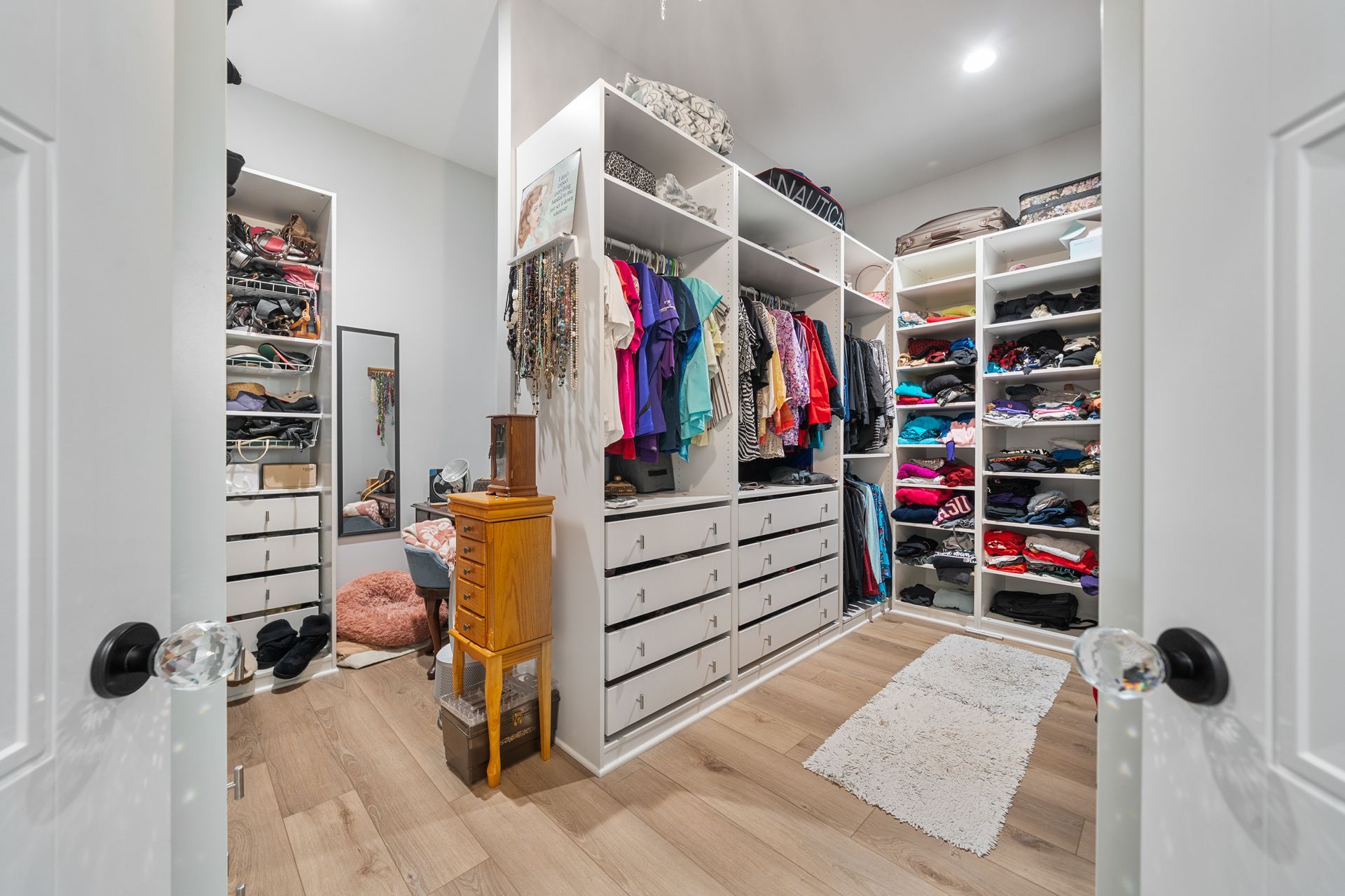 A walk in closet filled with lots of clothes and a mirror.