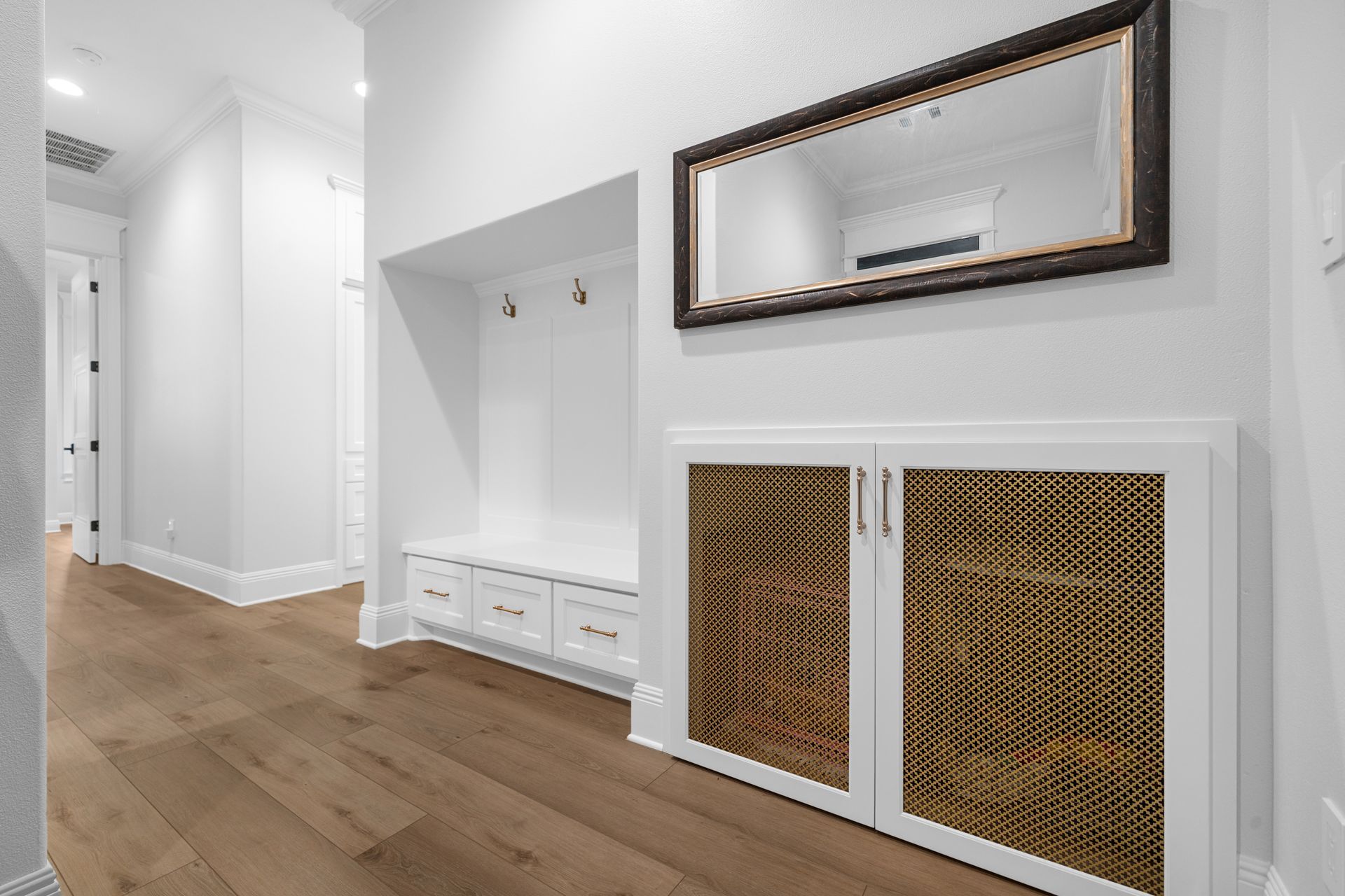 A hallway with hardwood floors and a mirror on the wall.