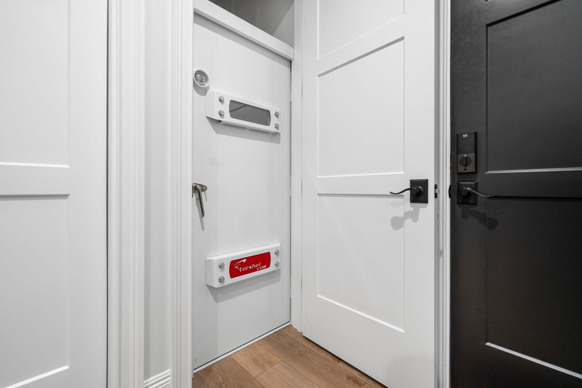A hallway with white doors and black doors in a house.