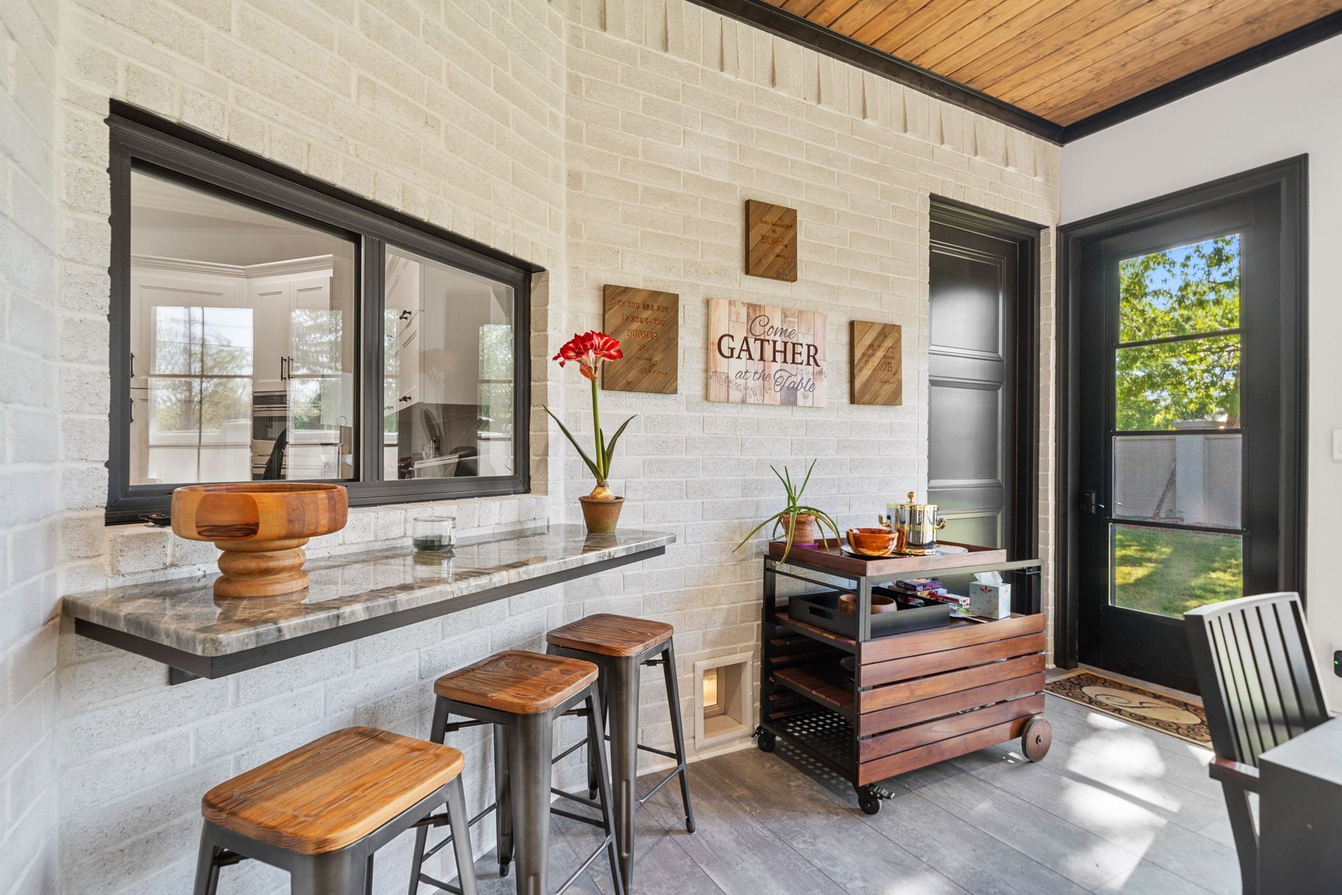 A kitchen with a bar and stools and a window.