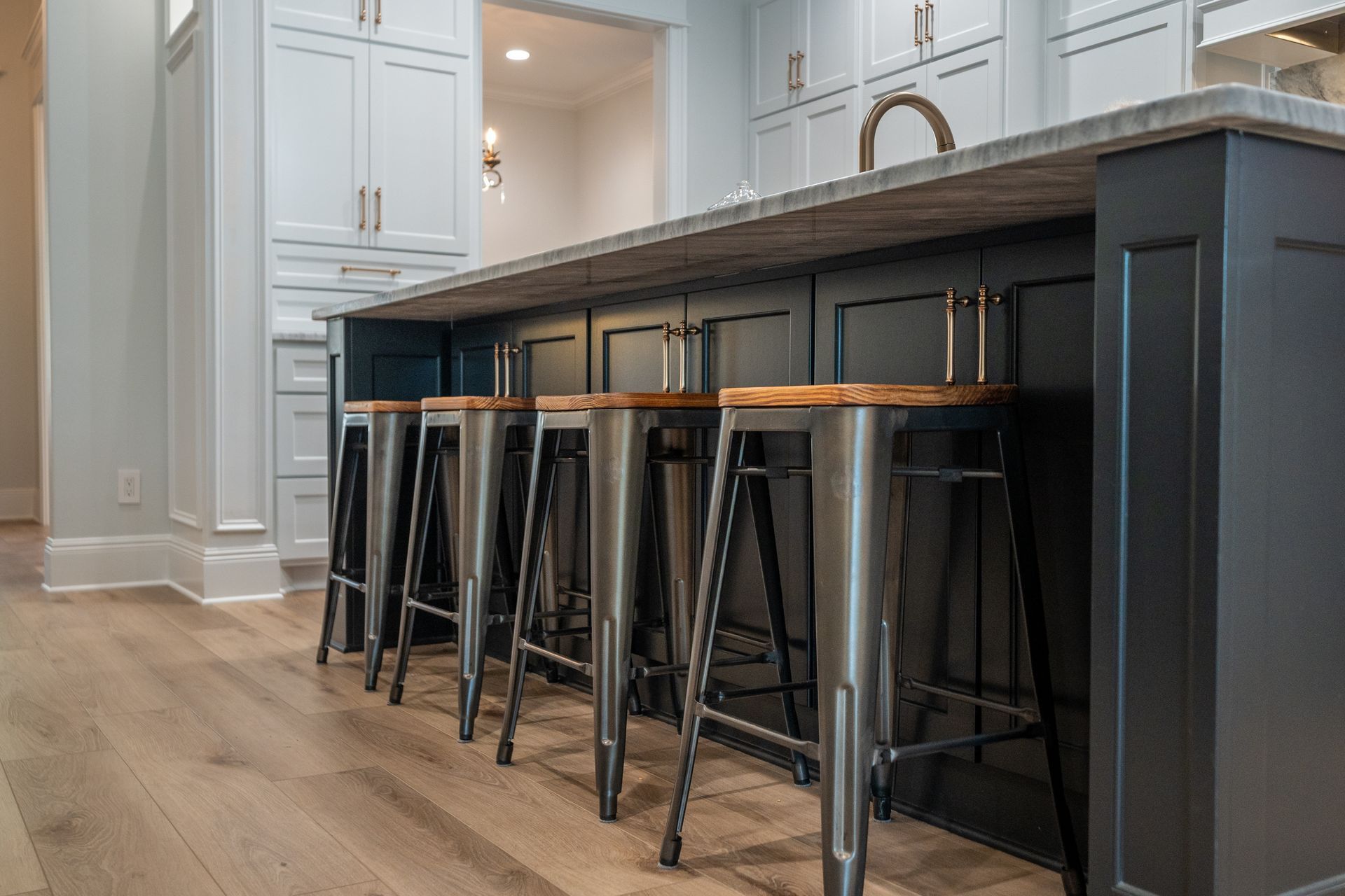 A row of bar stools are lined up next to a kitchen island.