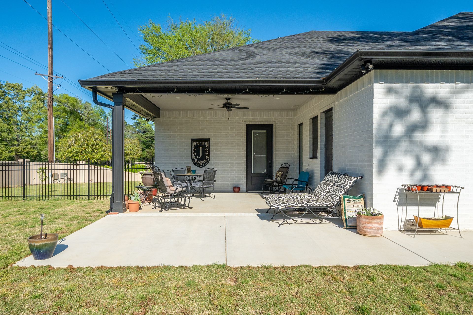 A white house with a covered patio and chairs in front of it.
