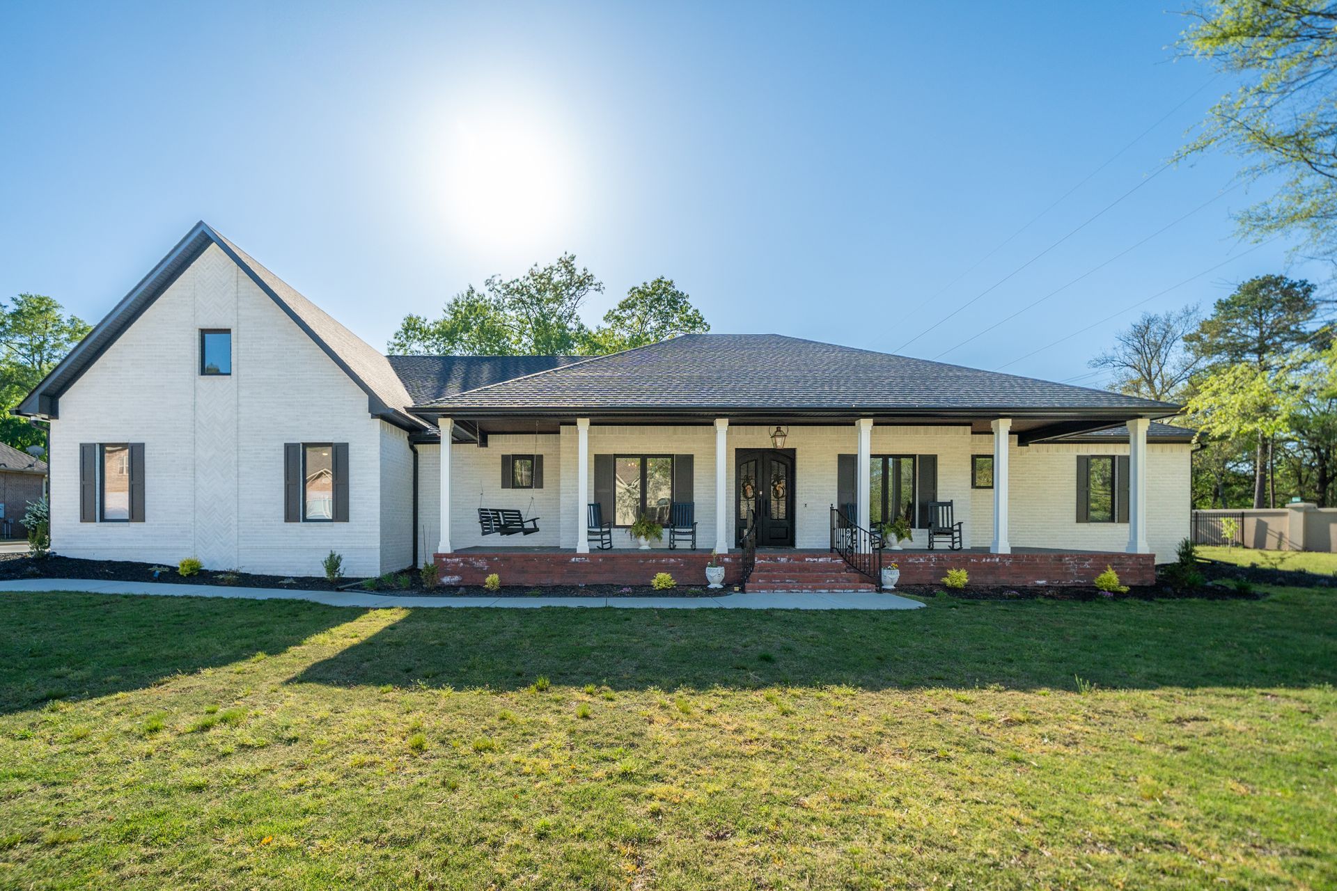A white house with a black roof is sitting on top of a lush green field.