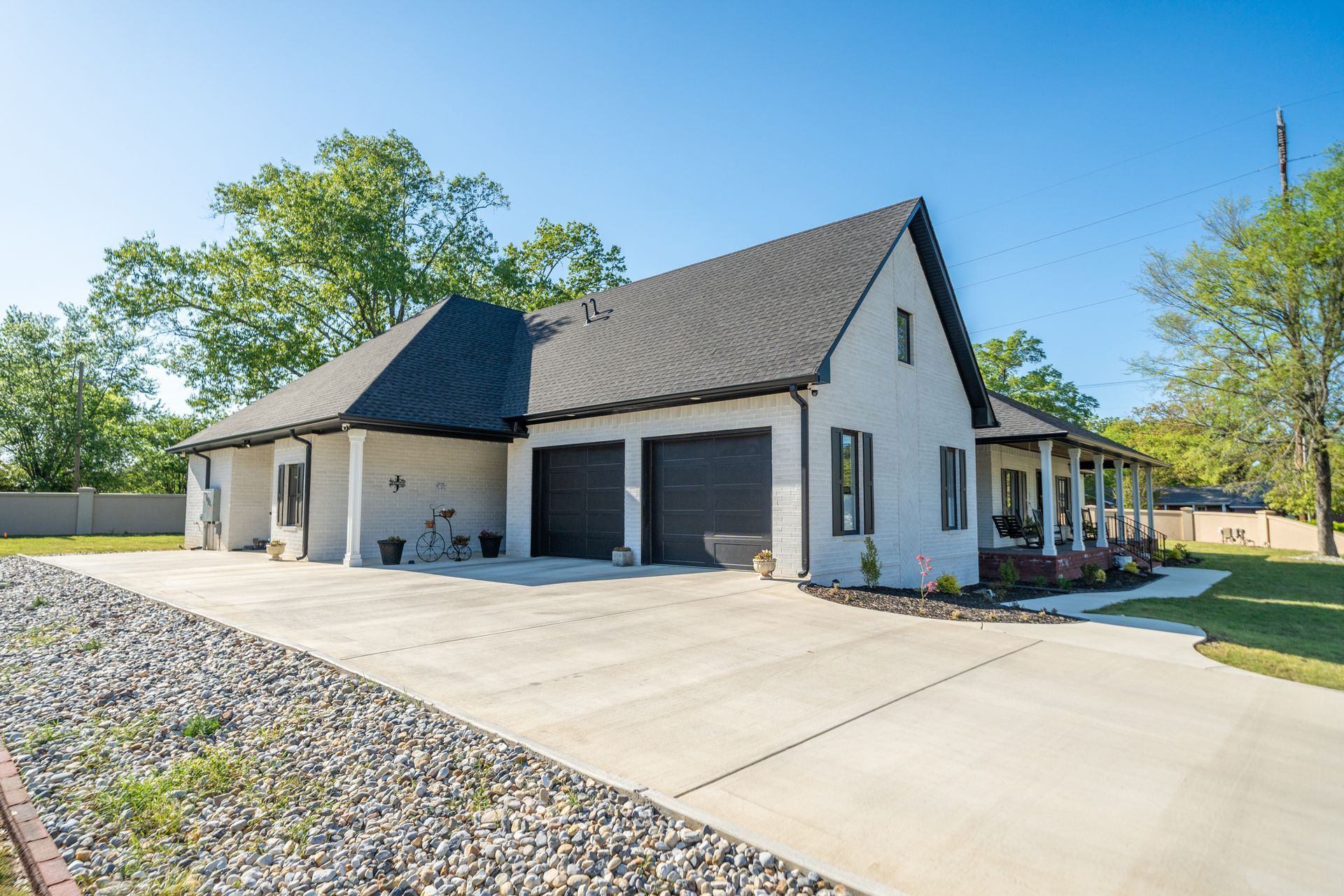 A large white house with two garages and a driveway.