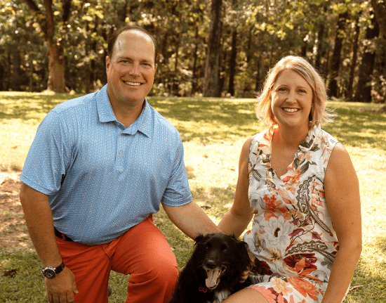 A man and a woman are posing for a picture with a dog.