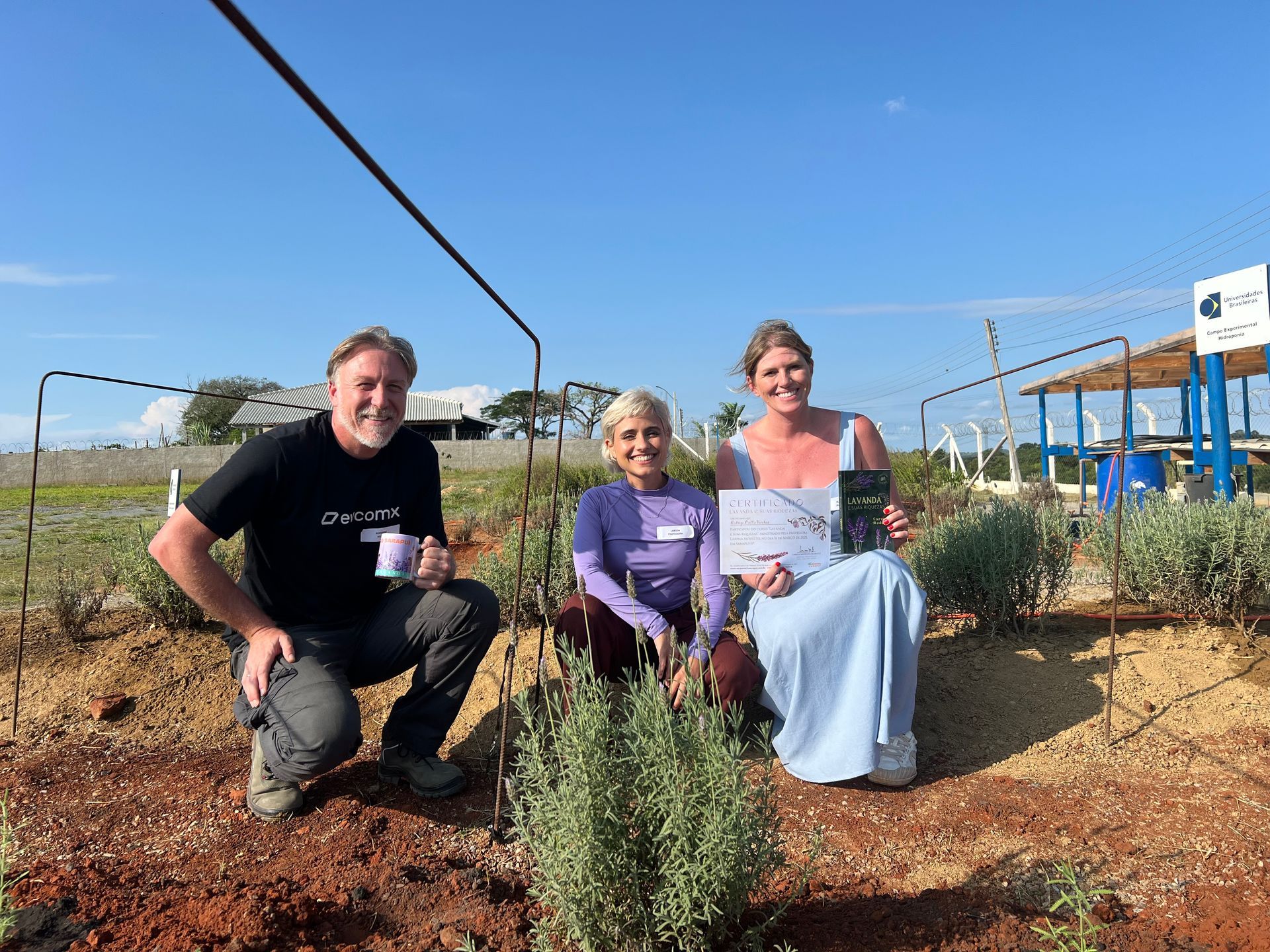 Professora Larissa e alunos na escola da lavanda segurando o livro e certificado do curso