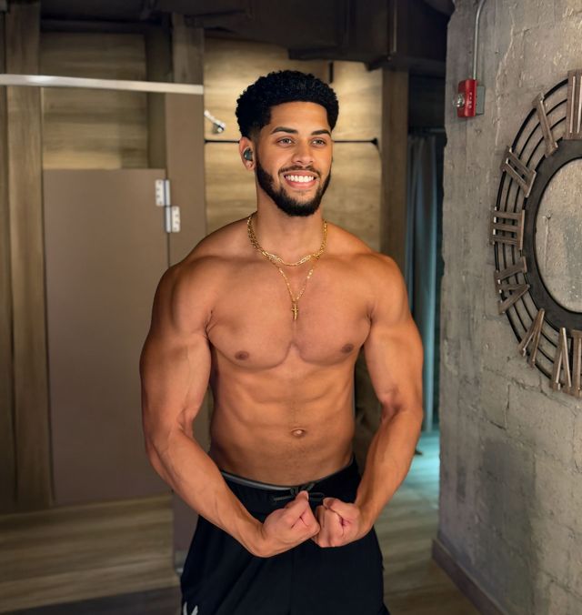 A shirtless man with a beard is standing in front of a mirror