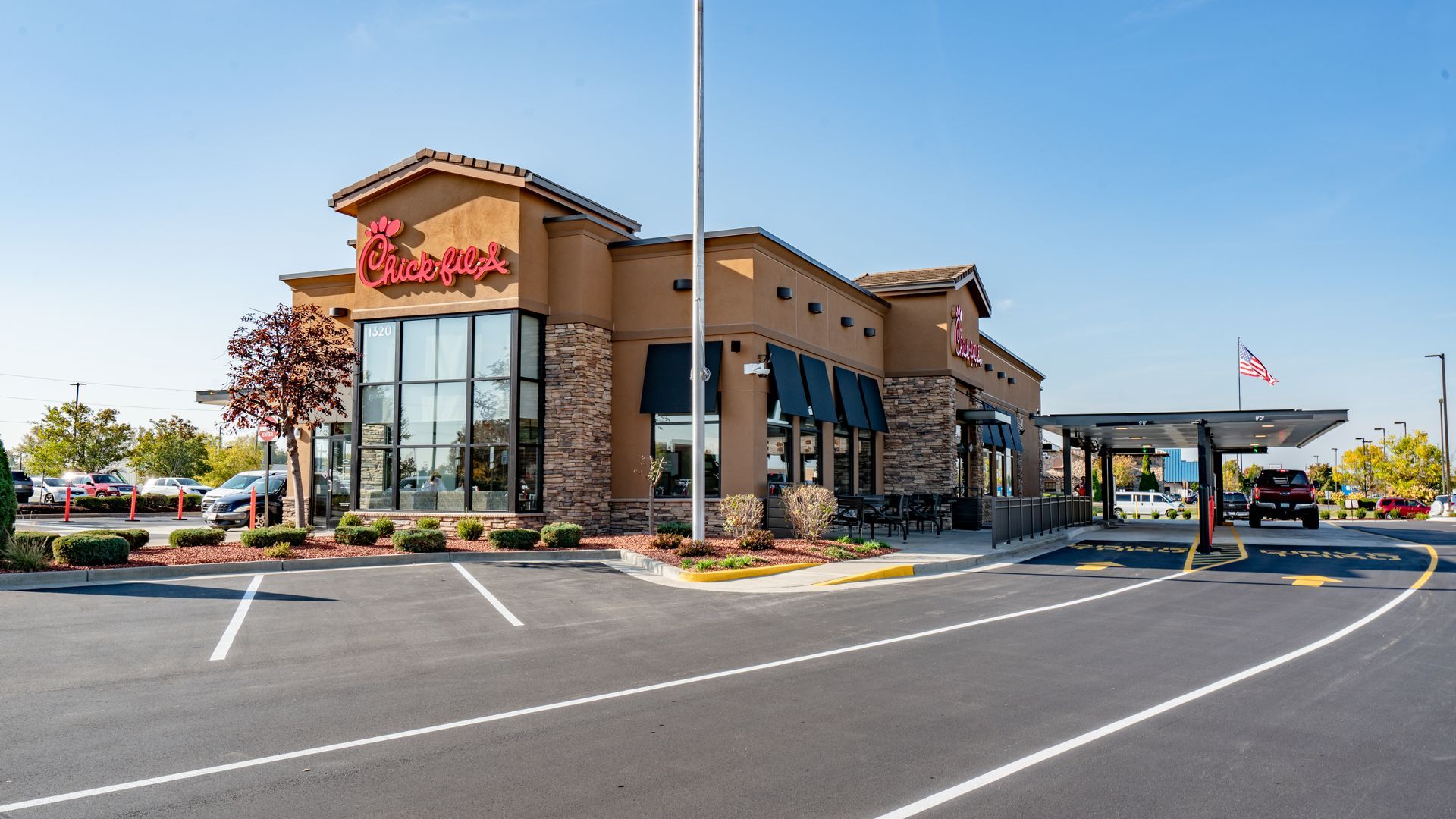 a chick-fil-a restaurant with a drive-thru and a parking lot in front of it .