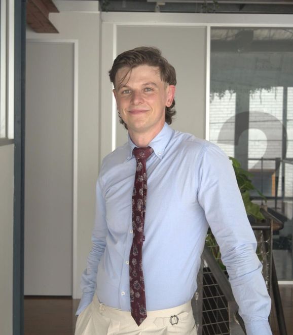 A man wearing a light blue shirt and a red tie