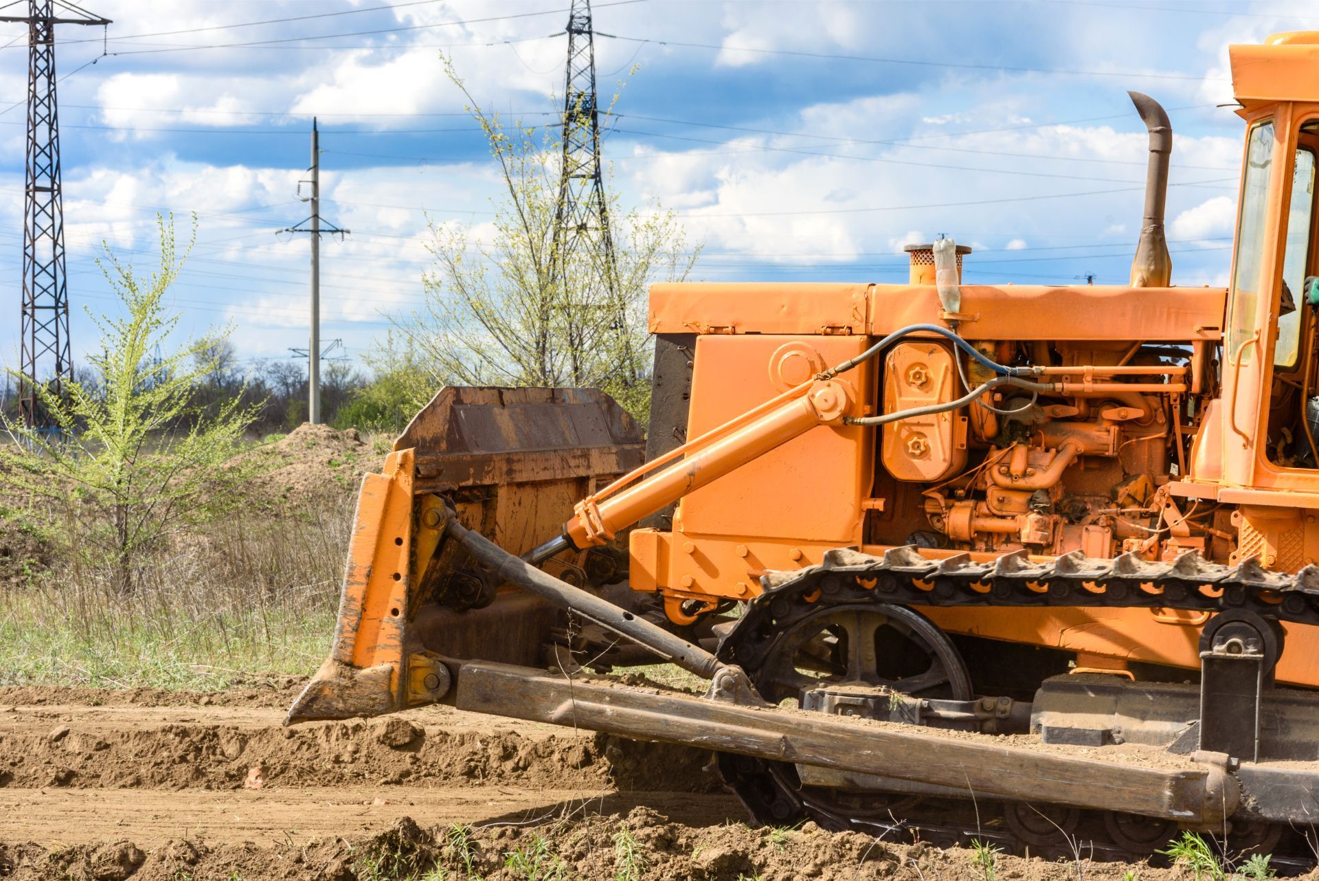 An orange bulldozer is moving dirt in a field.