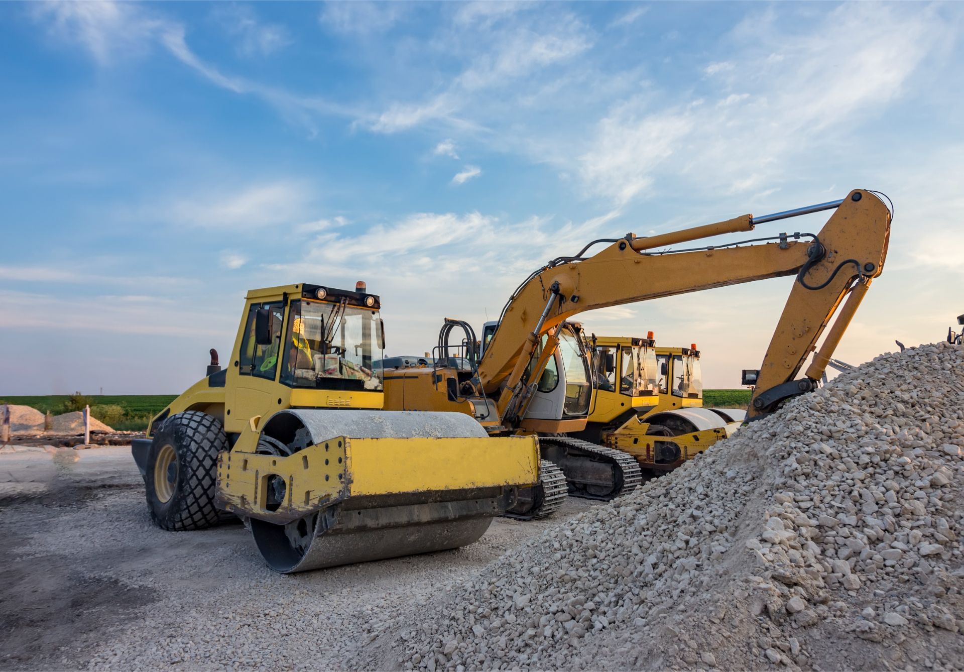 A bulldozer and a roller are sitting next to each other on a construction site.