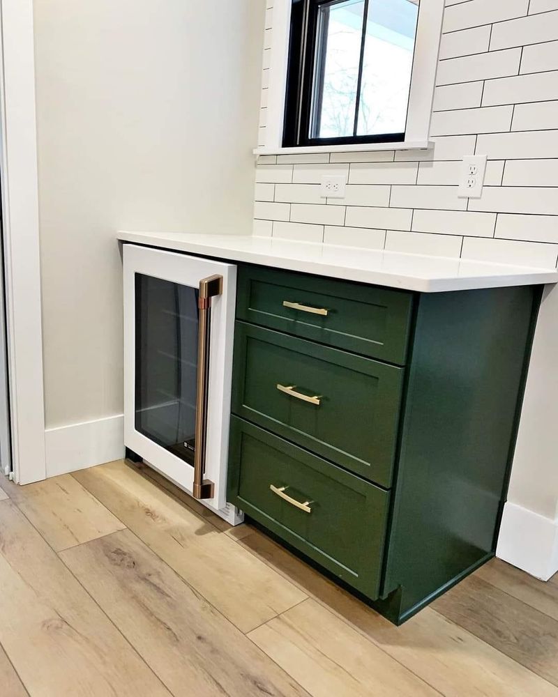 A kitchen with green cabinets and a wine cooler.