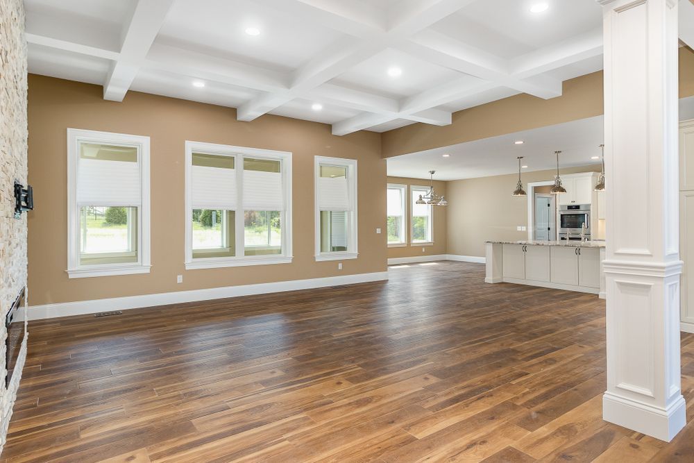 An empty living room with hardwood floors and a coffered ceiling.