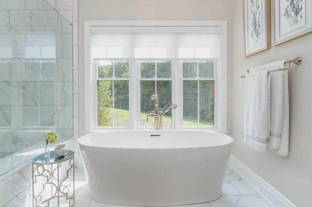 A bathroom with a tub , shower , and window.