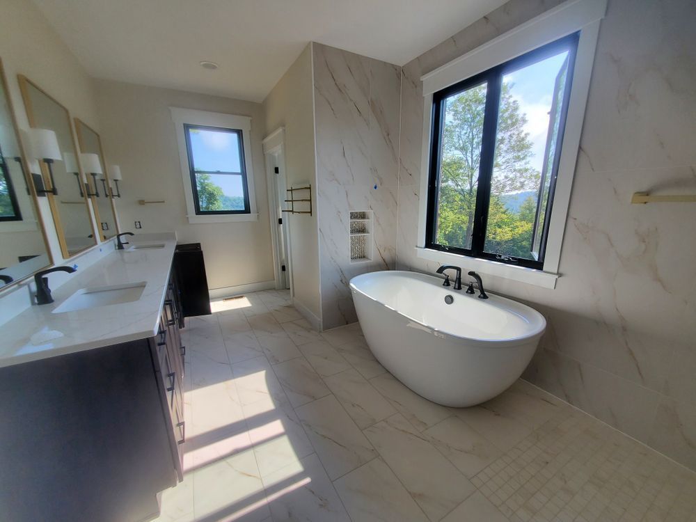 A bathroom with a tub , sinks , mirrors and a window.