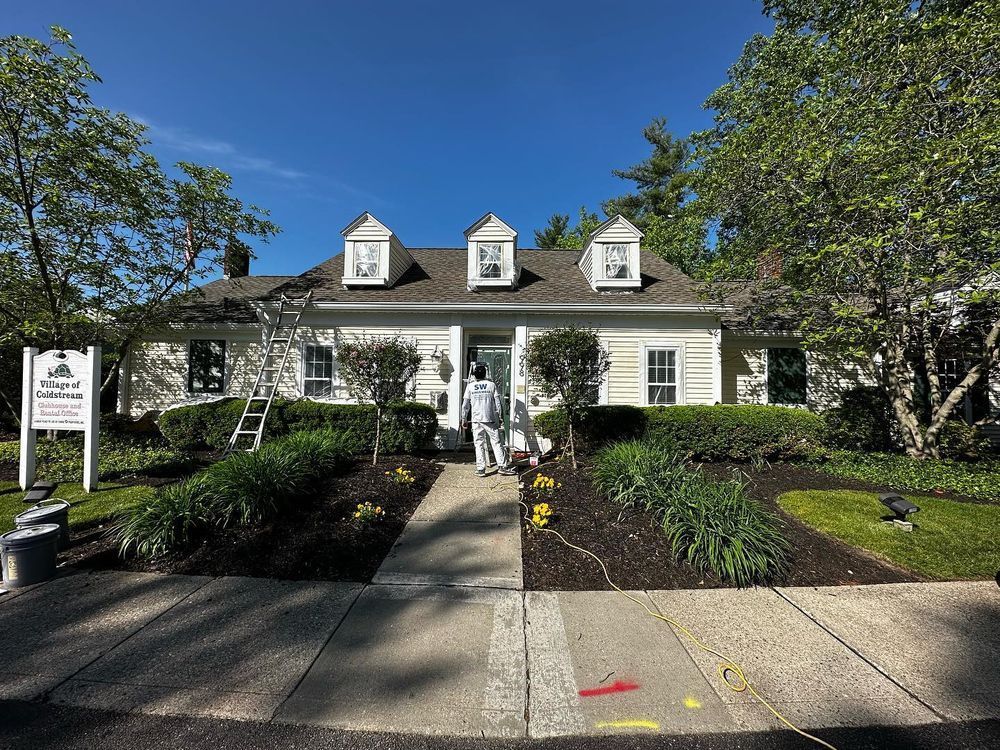 A man is standing in front of a white house.