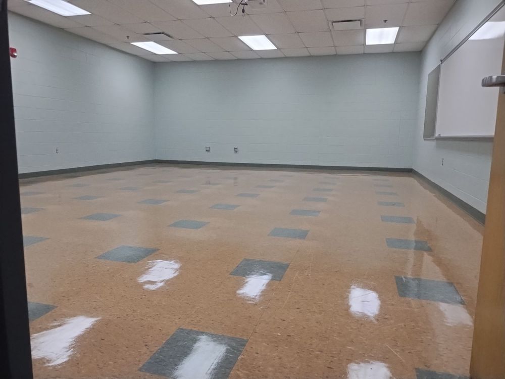 An empty room with a tiled floor and a white board on the wall