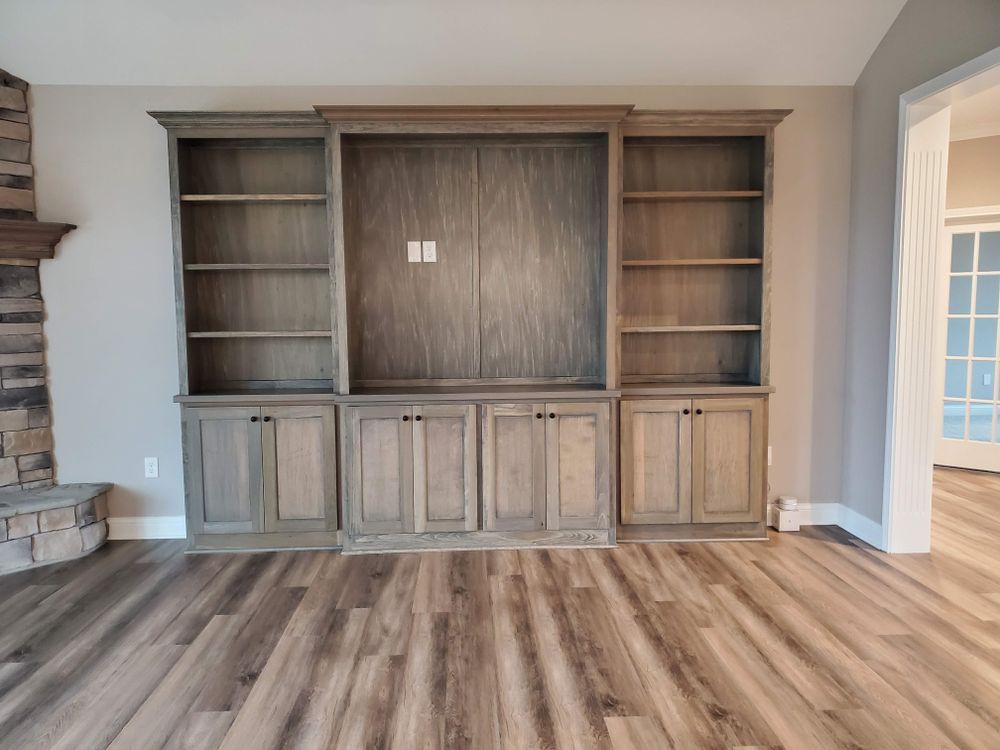 A living room with hardwood floors , a fireplace and a bookshelf.