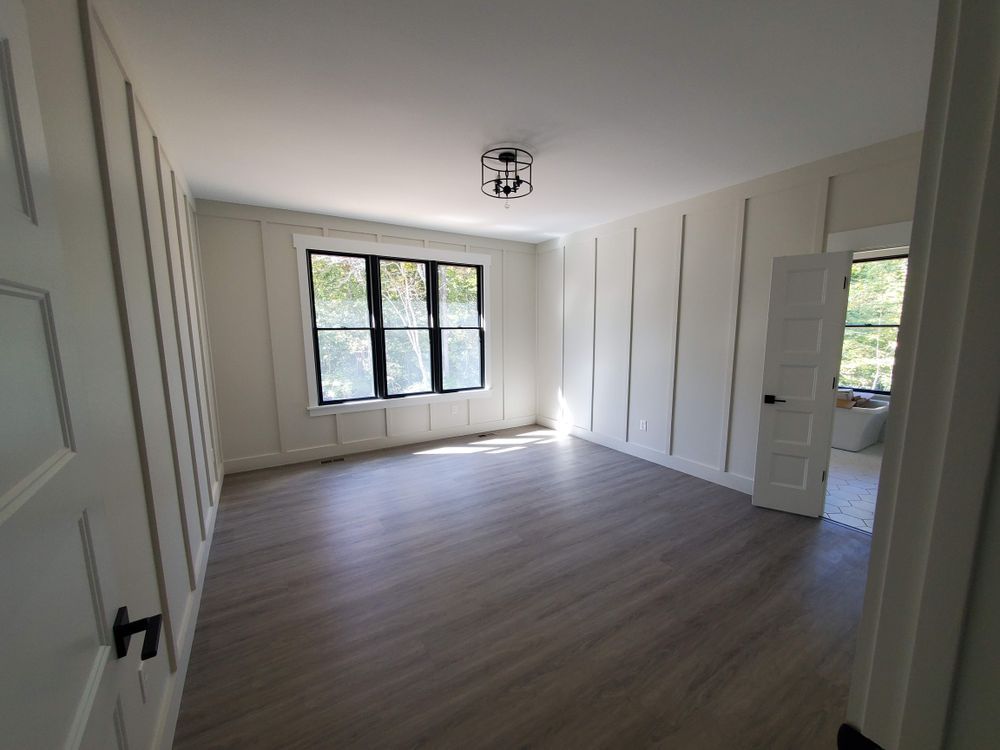 A large empty room with hardwood floors and white walls.