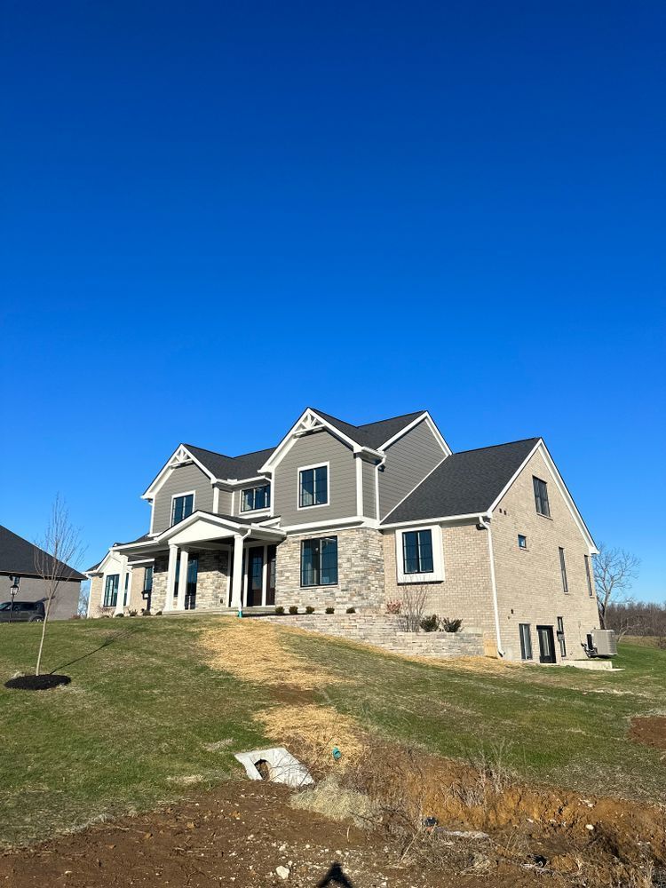 A large house is sitting on top of a grassy hill.