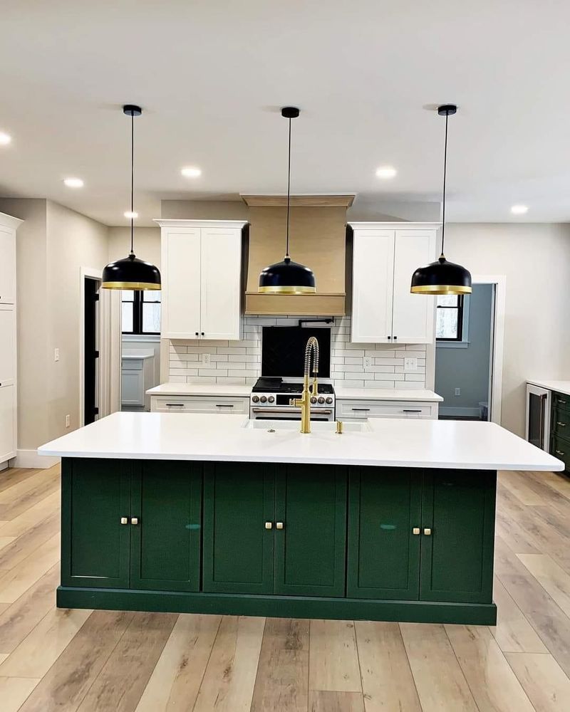 A kitchen with green cabinets , white counter tops , and a large island.