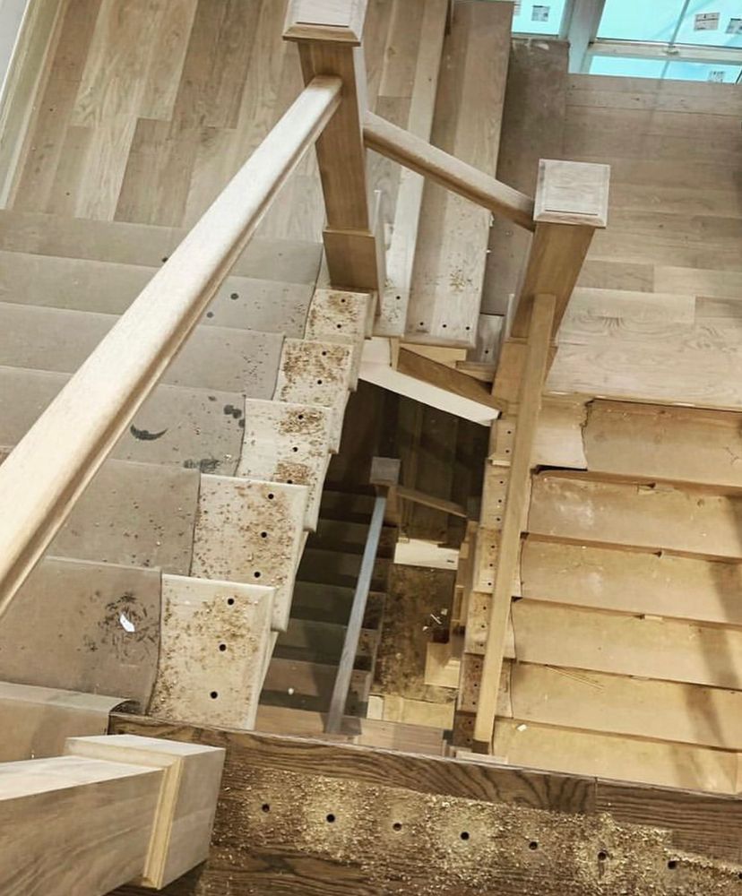 A wooden staircase with a wooden railing is under construction