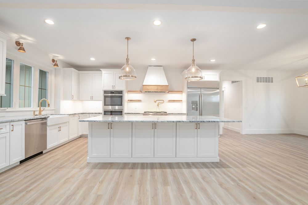 An empty kitchen with white cabinets and stainless steel appliances.
