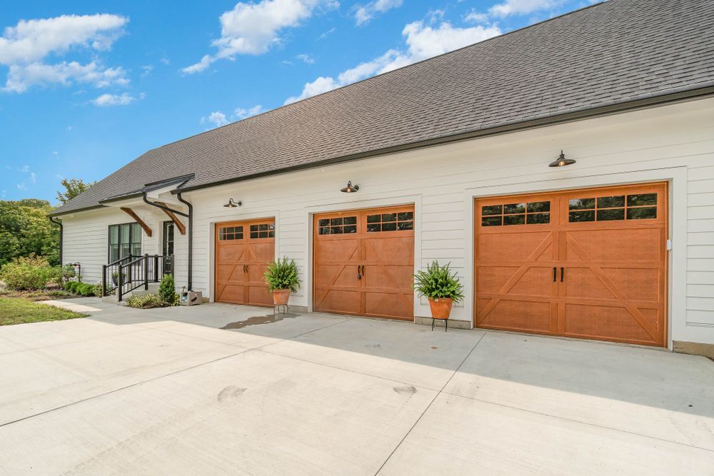 There are three garage doors on the side of a house.
