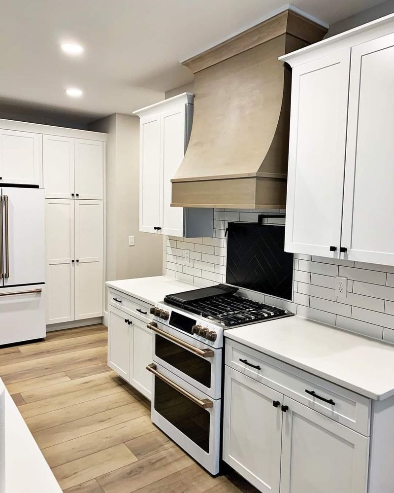 A kitchen with white cabinets , a stove and a refrigerator.