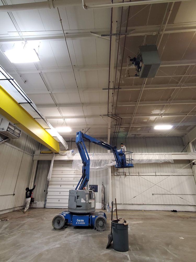 A man is painting the ceiling of a building with a lift.
