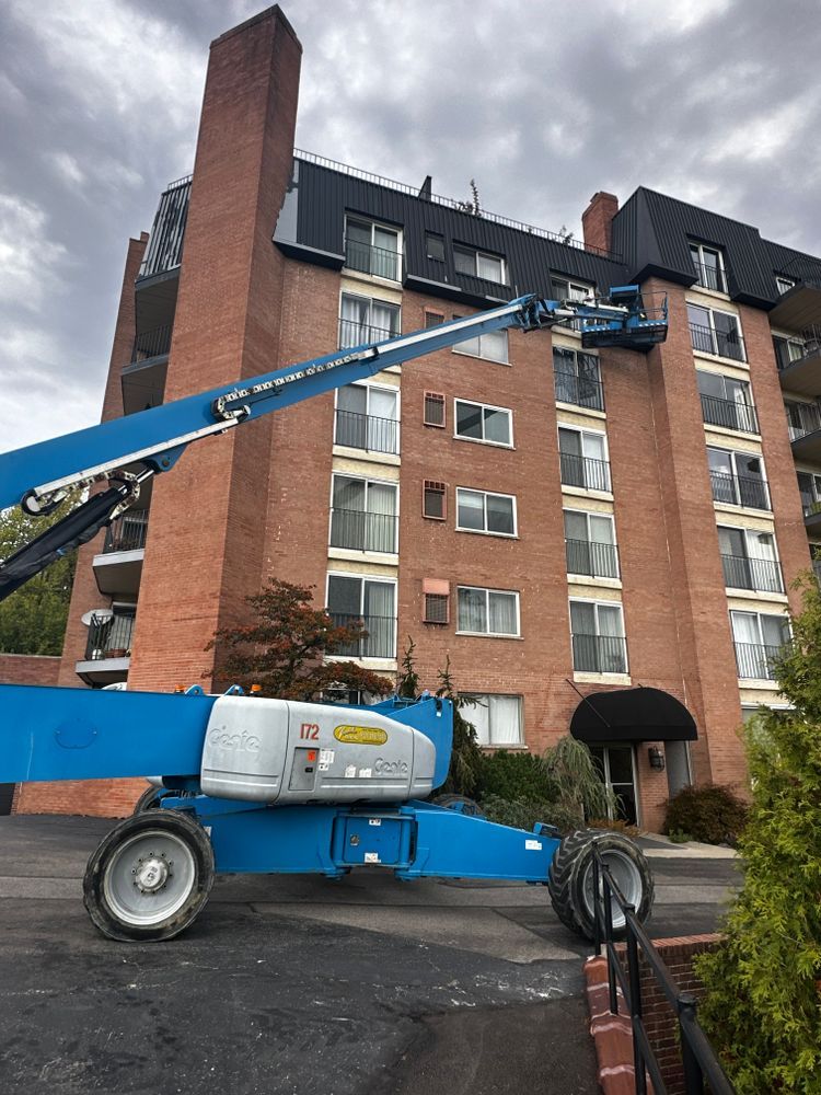 A blue crane is parked in front of a tall brick building.