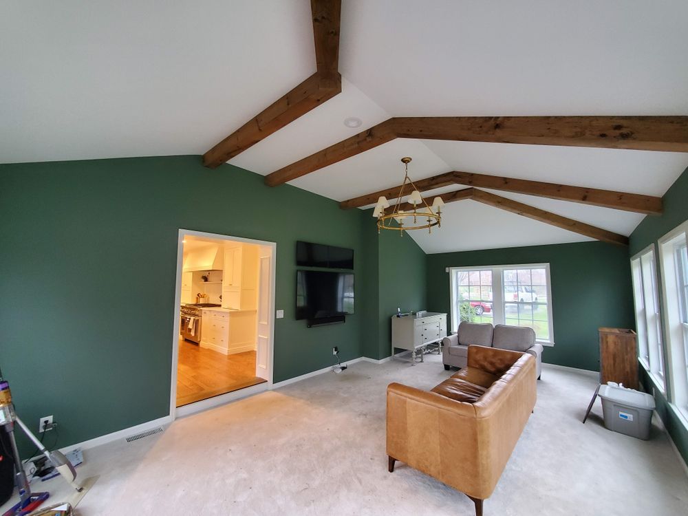A living room with green walls and wooden beams.