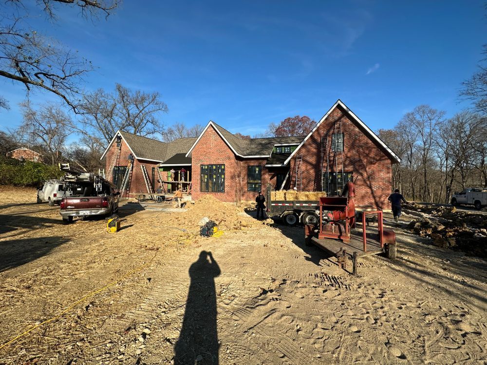 A large brick house is being built in a dirt field.