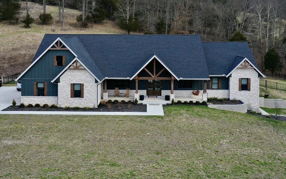 A large house with a blue roof is sitting in the middle of a grassy field.