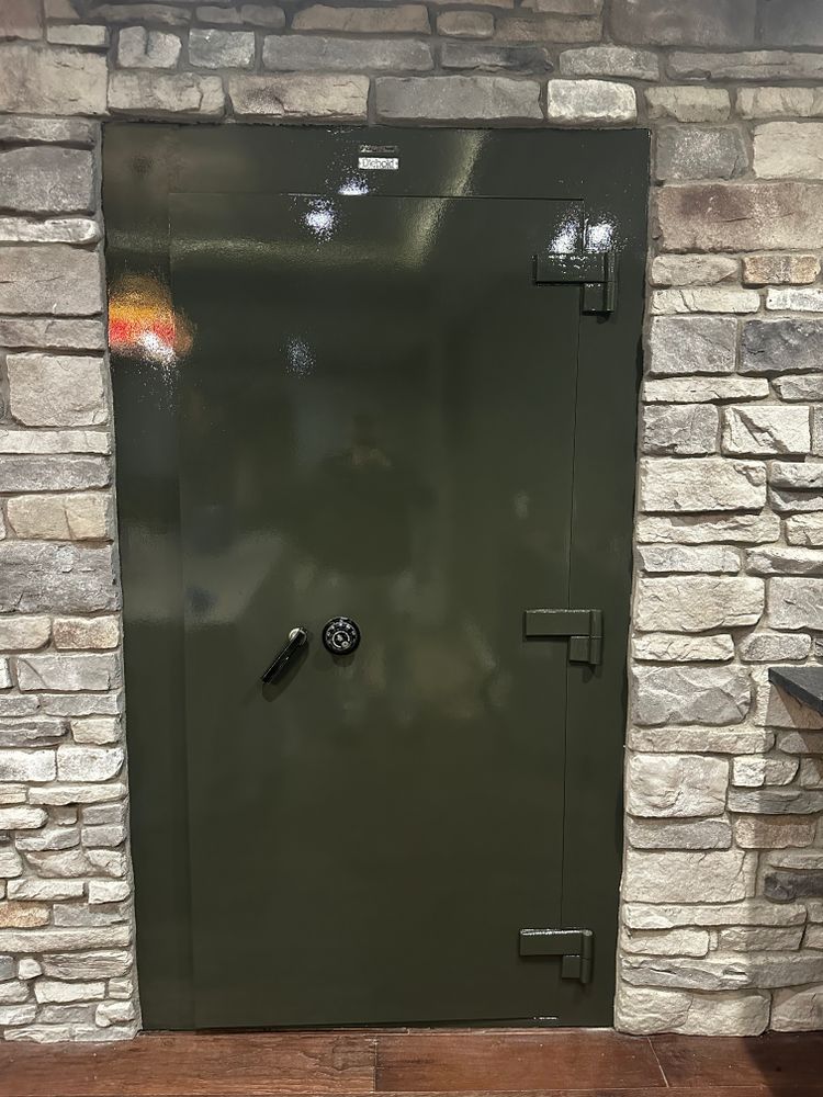 A green safe door is sitting in a stone wall.