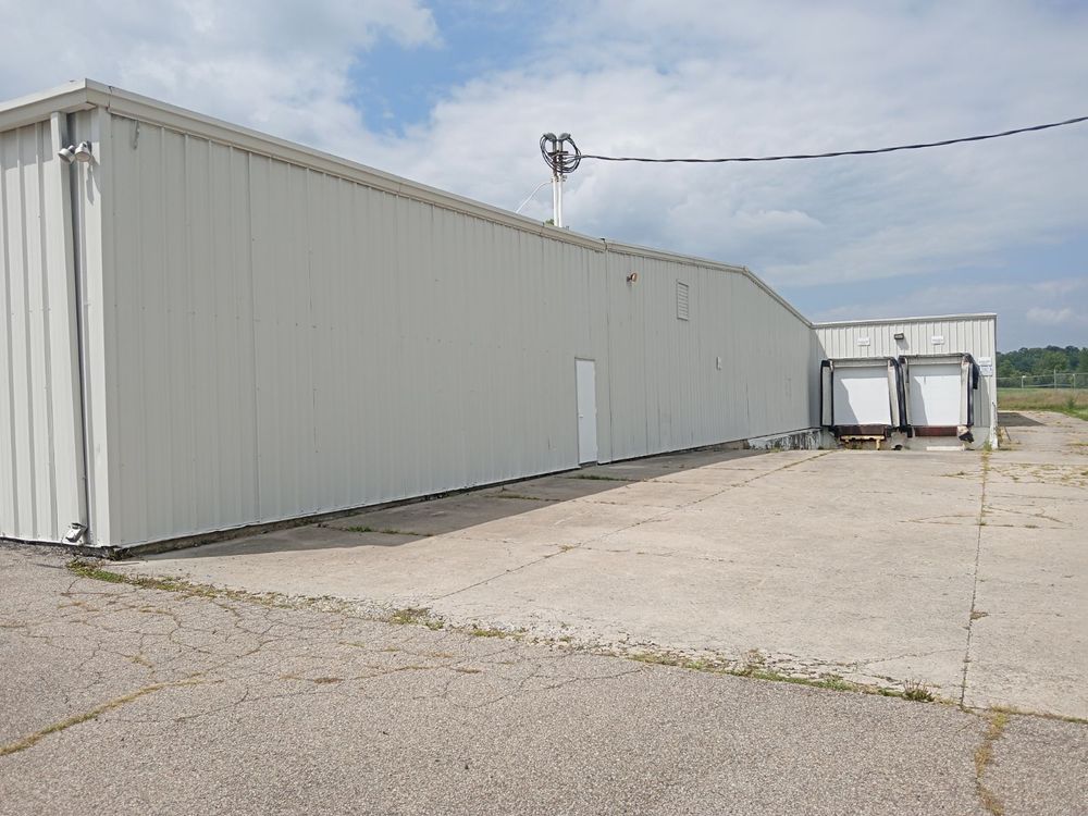 A large white building is sitting on top of a dirt field.