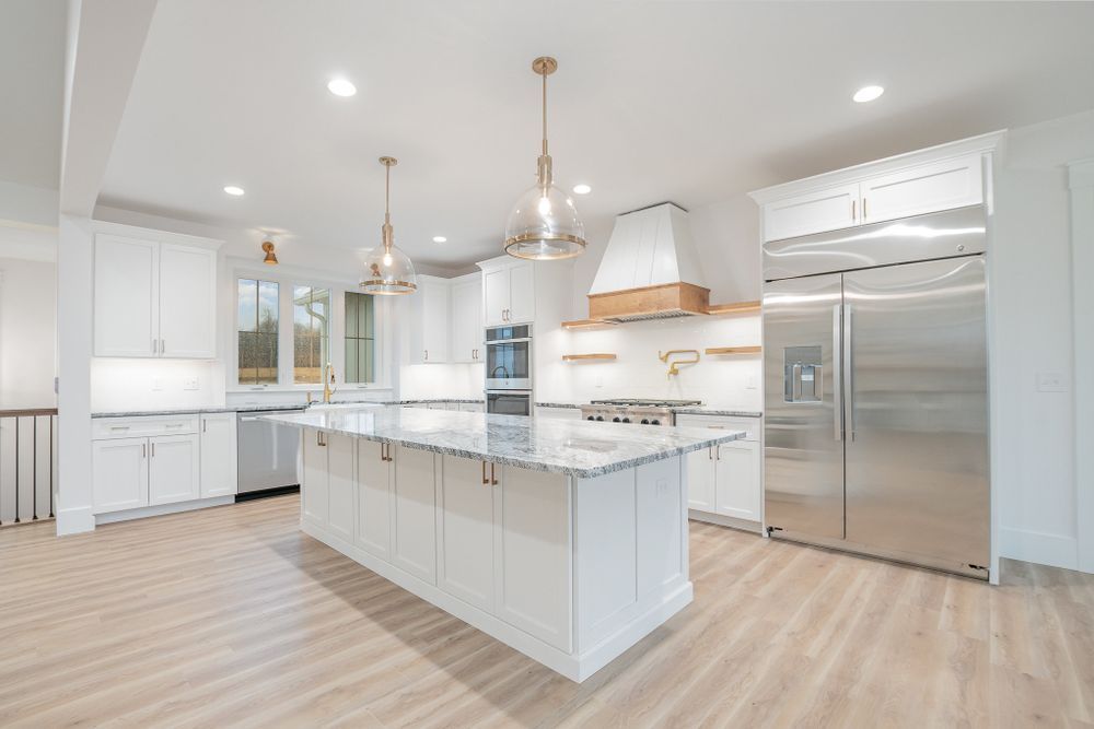 A kitchen with white cabinets and stainless steel appliances and a large island.