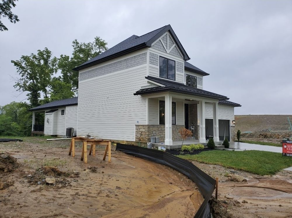 A white house with a black roof is being built.