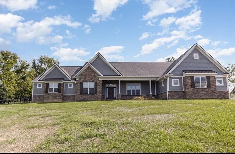 A large house with a lot of windows is sitting on top of a lush green field.