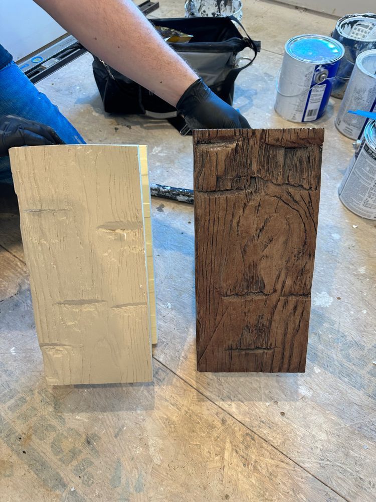 A person is painting a piece of wood on the floor.