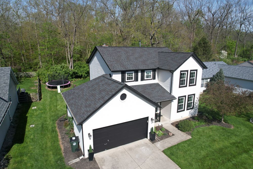 An aerial view of a white house with a black garage door.