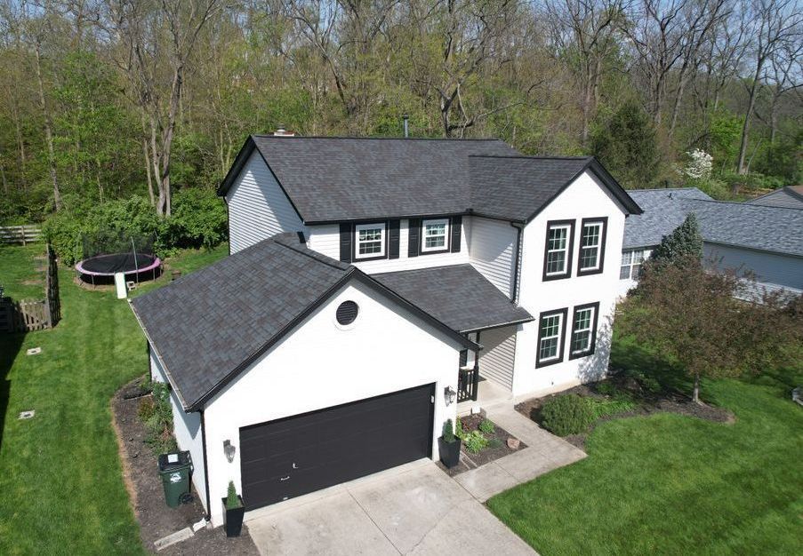 An aerial view of a white house with a black garage door.