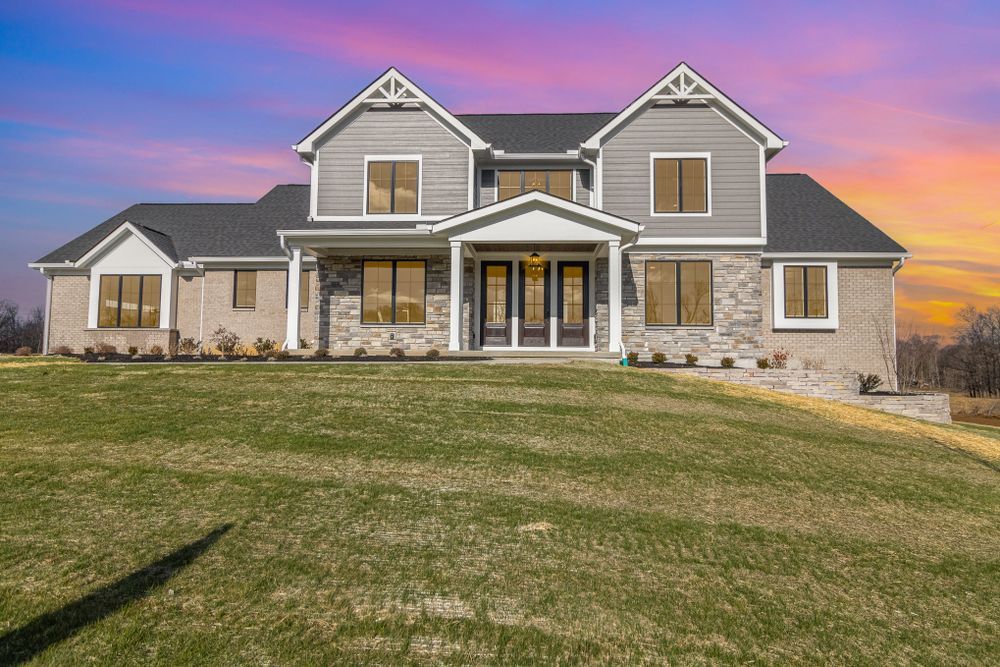 A large house with a lot of windows is sitting on top of a lush green field.