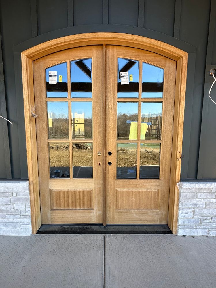 A wooden door with a reflection of a building in the glass