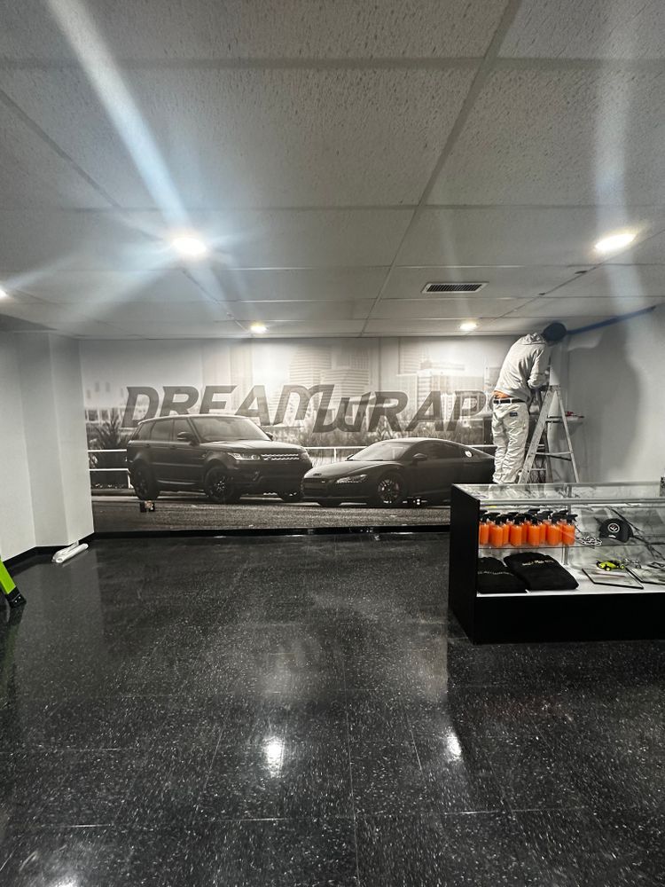 A man is painting a wall with a picture of cars on it.