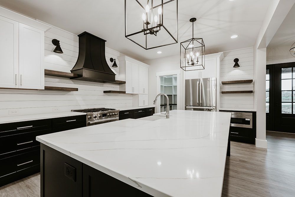 A kitchen with black and white cabinets and a large island.